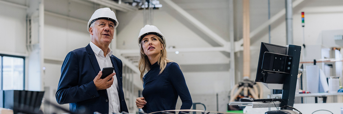 Man and Woman with hardhats in a manufacturing facility Man and Woman with hardhats in a manufacturing facility