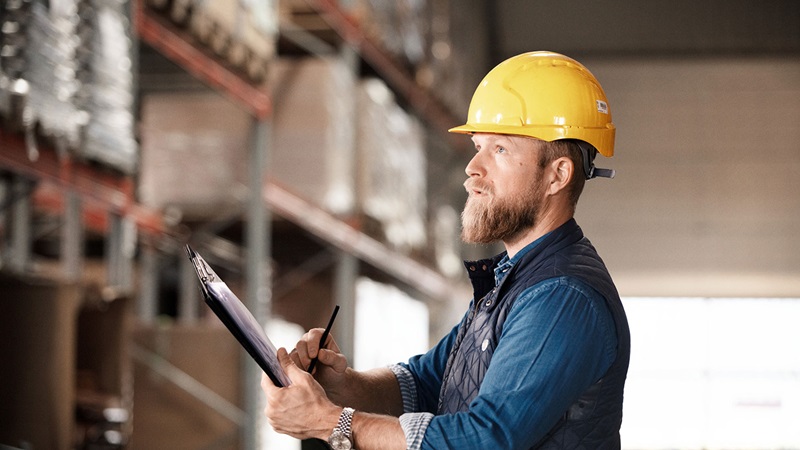 Male warehouse worker with clipboard and hardhat