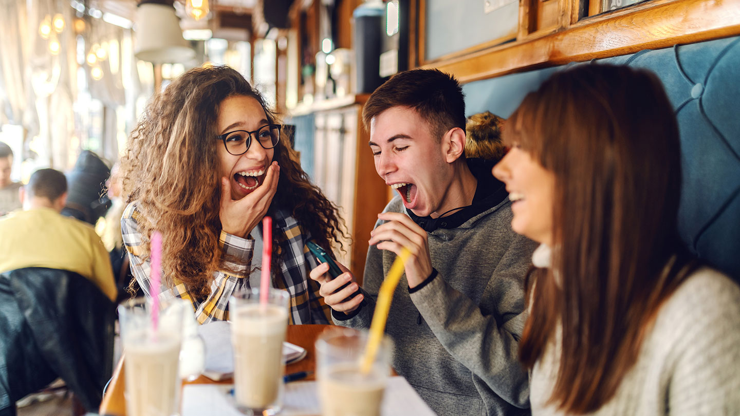 Teenagers sitting in cafe enjoying milkshakes Teenagers sitting in cafe enjoying milkshakes