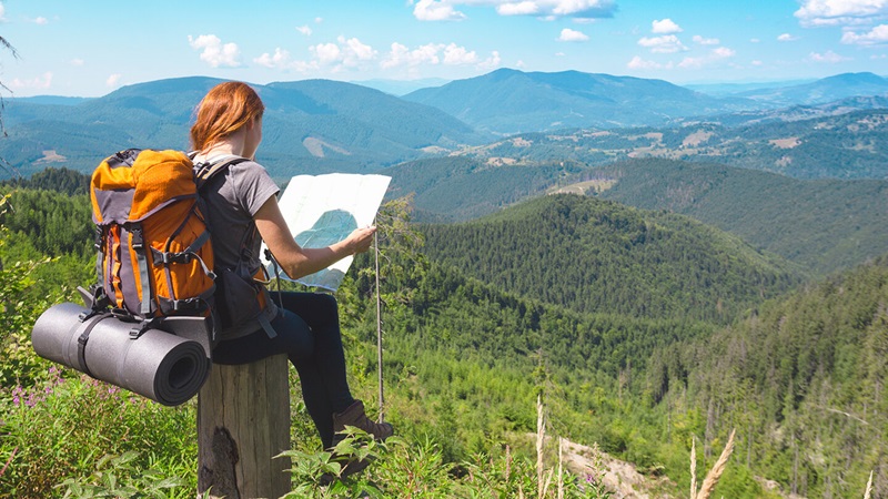 Girl with map surveying a valley