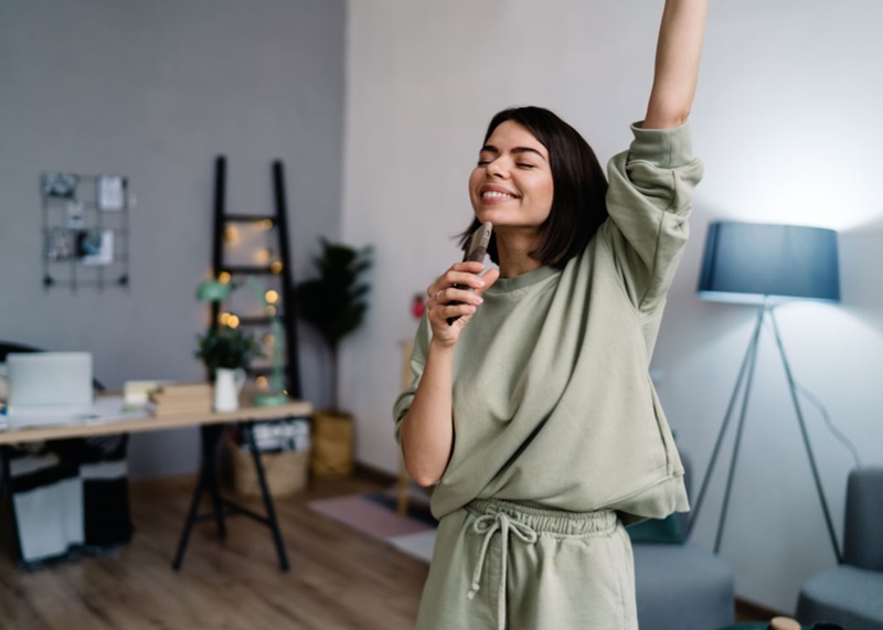 Young lady smiling with phone and hand in the air