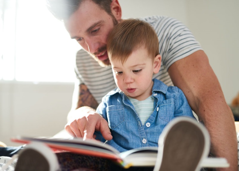 father reading book to toddler