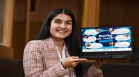 A person smiling at camera, holding a laptop with 'Maths Week' graphics on it.