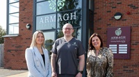 Three people standing together outside of Armagh Dental Clinic, smiling.