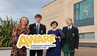 AWARE NI and Danske Bank partnership ends Four people stand outside a school holding an AWARE NI sign.