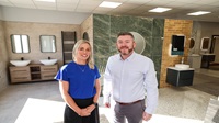 Bathshack opens two new showrooms creating eight jobs supported by Danske Two people stand beside each other inside a bathroom and tile showroom.