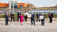 Nine people in business wear standing outside. Two are holding signs saying '#BuildBackResponsibly' and 'Climate change'.