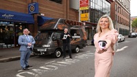 Three people standing outside - one is holding a coffee cup and one a bag of coffee beans, and behind them is a branded coffee van called 'Suitor Coffee'